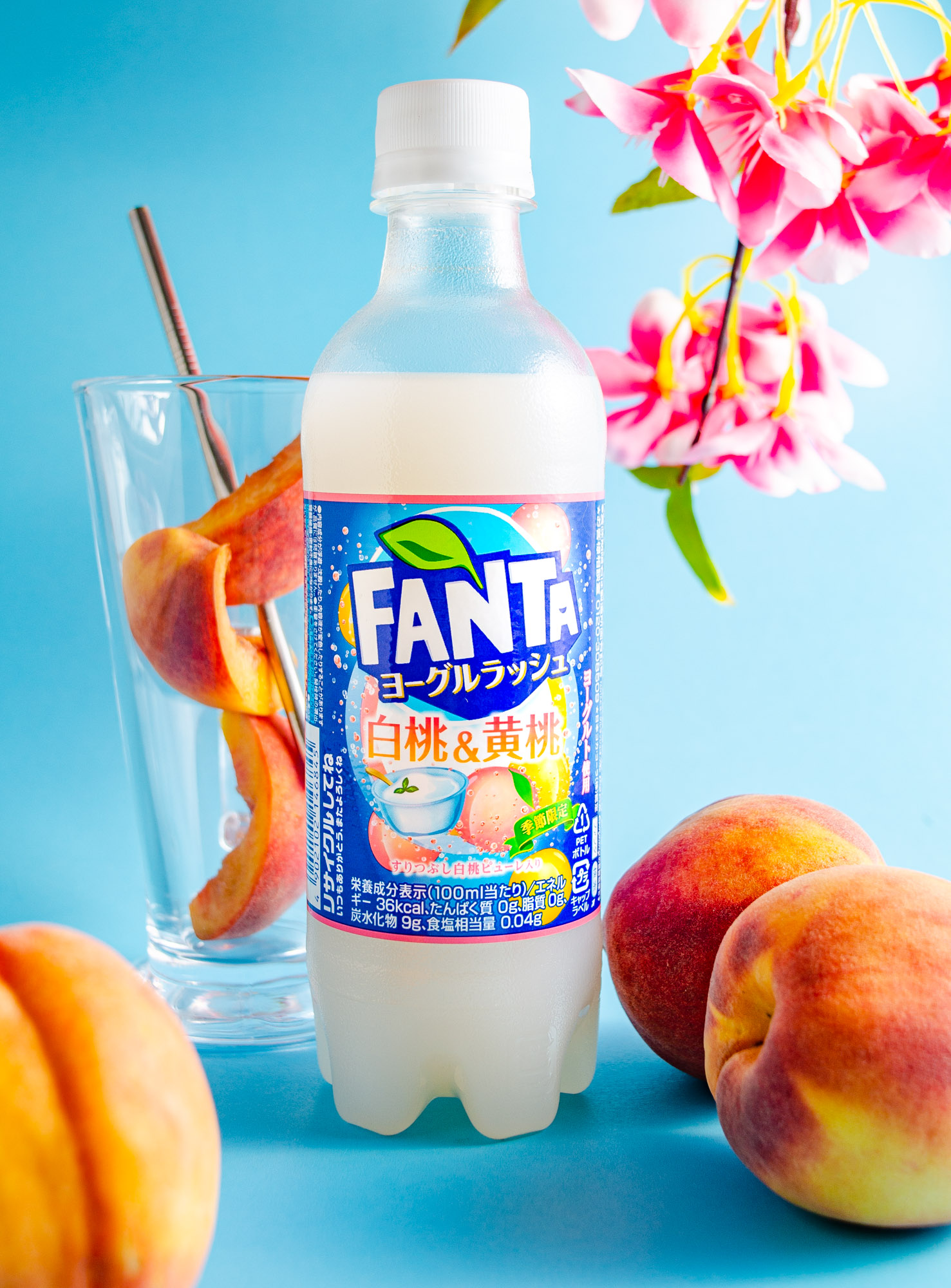 Fanta Peach yogurt with blossoms and sliced peaches on a blue background