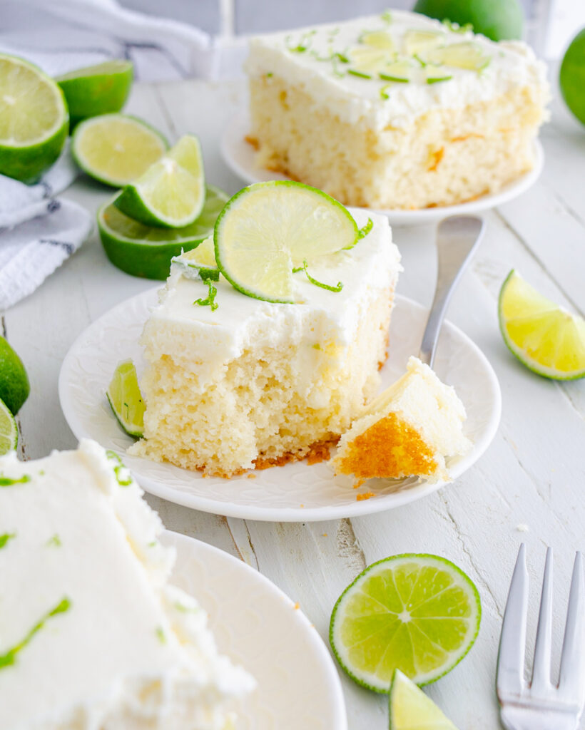Key lime poke cake on a white plate garnished with limes